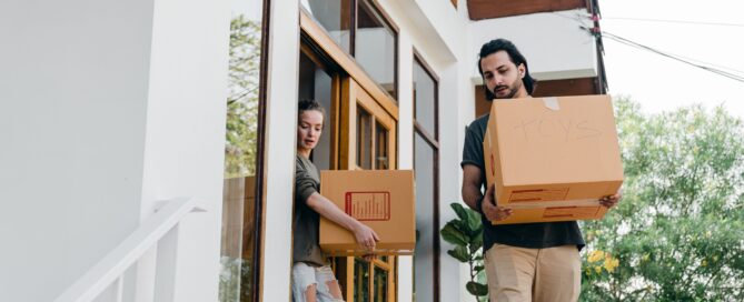 A couple carrying boxes downstairs