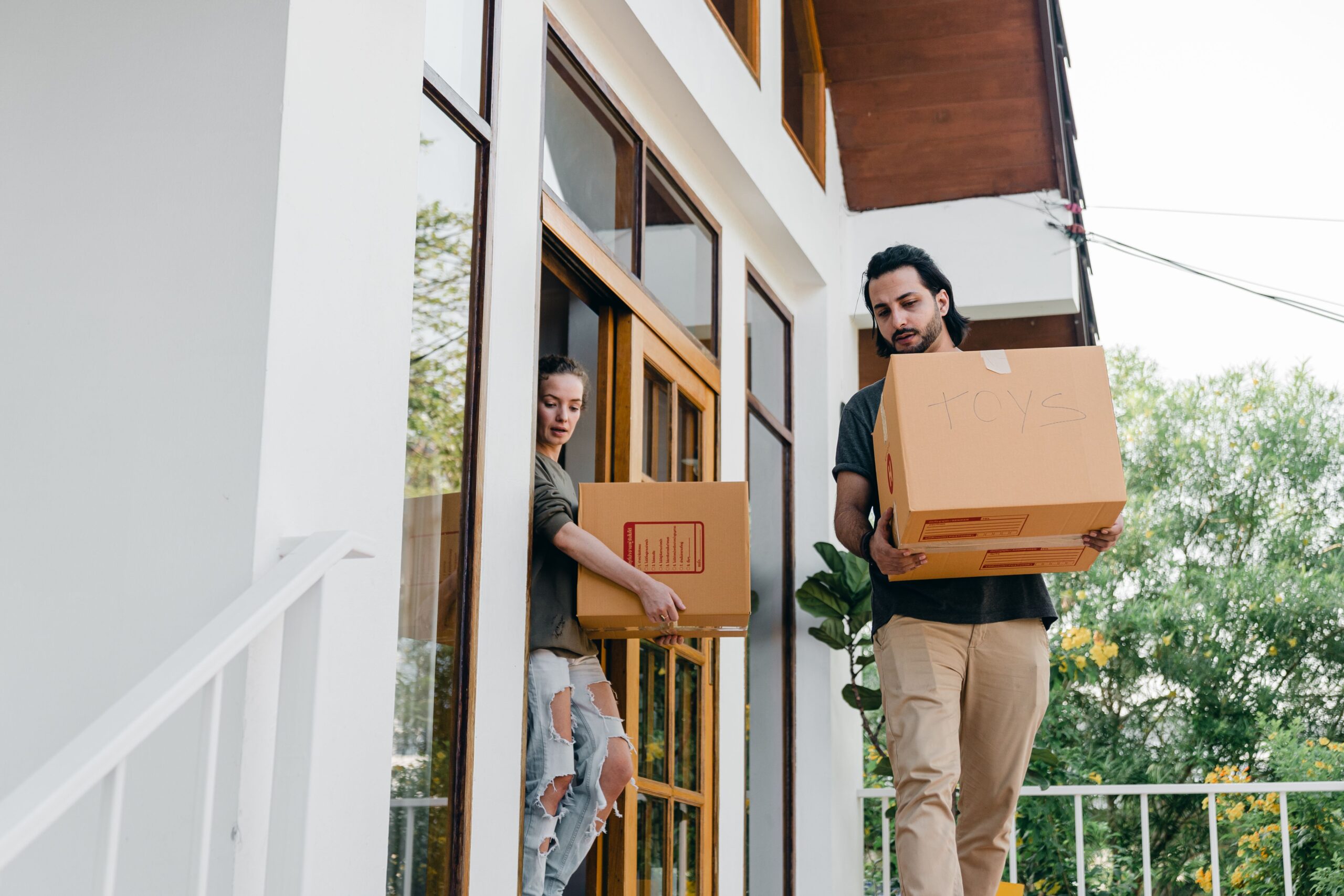 A couple carrying boxes downstairs
